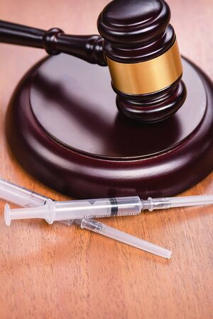 Judge's gavel and syringes on a wooden table. The concept of the fight against drugs and drug addiction. Court hearing against drugs. Medicine and law.の写真素材