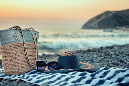 Summer women's beach accessories for your sea holiday: straw hat, sunglasses, beach bag and striped towel, seashell.の写真素材