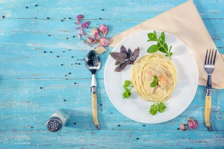 Dish standing on a blue wooden table, a plate with Italian pasta and chicken with a sauce of Provencal herbs, decorated with herbs, salt and garlic.
の写真素材