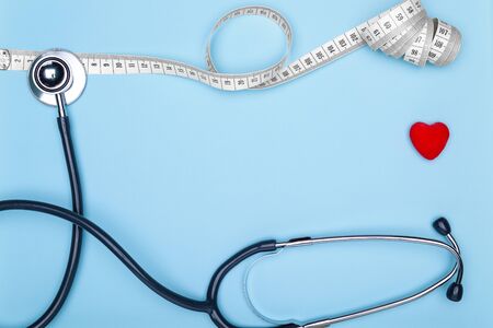 Flexible meter, statoscope and red heart on blue background-concept of sports and fitness.Closeup of a red heart, mya meter and stethoscope on blue background.Concept of healthy lifestyle.の写真素材