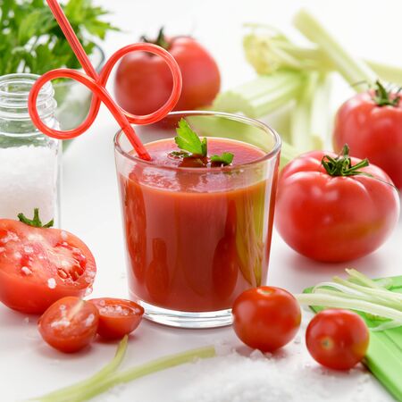 Tomato juice in glass with celery, cherry tomato, white wood background, closeupの写真素材