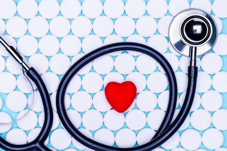 Background of white pills. Statoscope on the background of white pills and a red heart.Global healthcare concept. Antibiotic resistance.の写真素材