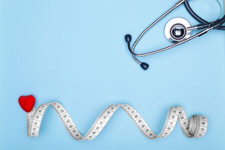 Concept of healthy lifestyle.Flexible meter, statoscope and red heart on blue background-concept of sports and fitness.Closeup of a red heart, mya meter and stethoscope on blue background.の写真素材