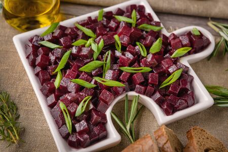 
Red beet salad with onion and olive oil. next to the table lie a fork and a knife on a beautiful napkin. Close-up.の写真素材