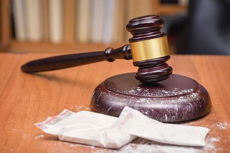 Court for the sale of drugs. Verdict for the distribution of drugs. White powder on the judge's gavel. Drugs on the table of the judge.の写真素材