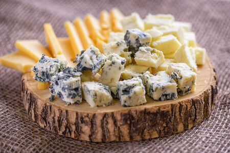Pieces cheese on natural background. Natural cheeses slices, side view. Cheese with mold close-up. Different sorts cheese on wooden board.の写真素材