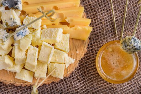 Cheese with mold and honey close-up. Pieces cheese on natural background. Honey and cheese pieces. Sliced natural cheeses, top view. Different sorts cheese on wooden board. の写真素材