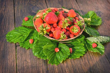 Ripe, juicy and red, strawberry in a plate close-up, on a wooden wet background, taken after the rain.の写真素材