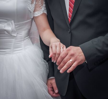 Young bride and groom put each other's gold rings on a finger and show them on their hands.の写真素材