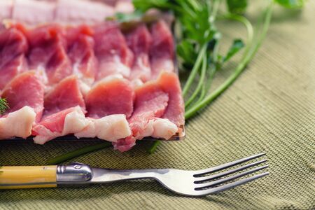 Raw chopped bacon for cooking. Fresh cooked food. Fresh cold sliced bacon on the background of...