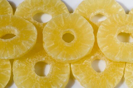 Yellow pineapple candies, sliced in round slices in powdered sugar, on a white background.の写真素材