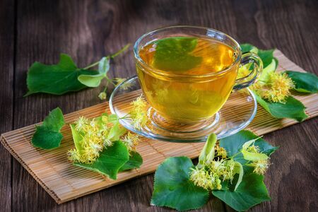 A cup with fragrant lime tea, standing on a wooden table, in the rays of sunlight.の写真素材