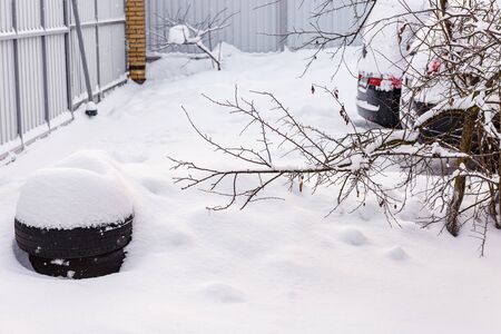 Car tires on white snow. Snow-covered car tires. Summer tires in snowdrift of snow close-up. It's time to change summer tires for winter. Car tires lying in the courtyard of the house. の写真素材