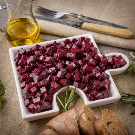 
Red beet salad with onion and olive oil. next to the table lie a fork and a knife on a beautiful napkin. Close-up.の写真素材