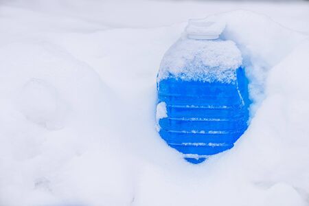 Non-freezing liquid for washing car glass in winter. Winter car wash glass liquid in the snow. Car non-freezing fluid in frost on snow. Blue liquid in frost during day.の写真素材