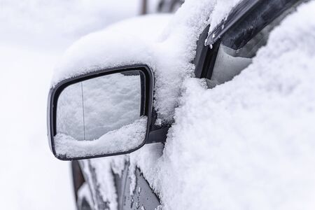 Car mirror in the snow close-up. Side mirror of car. Car standing in snow. Snowdrift snow by car. Snow covered car. Winter, snow, car in snowdrift.の写真素材