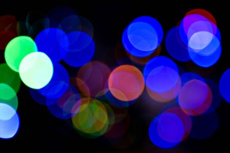 Bokeh colorful multi-colored lights yellow red blue green. Blurry lights Christmas mood. Lights from Christmas garlands defocused in beautiful bokeh. Copy space on background of multi-colored flashlights in blurry focus.の写真素材