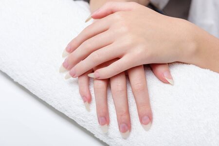 Woman holds hands on towel for manicure treatment procedure in spa salon. Beautiful hands of young woman close-up on towel. Spa treatments for nails. Space for text.の写真素材