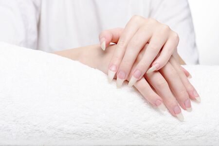 Beautiful hands of young woman close-up on towel. Spa treatments for nails. Space for text. Woman holds hands on towel for manicure treatment procedure in spa salon.の写真素材