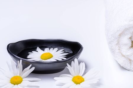 Natural oils for SPA. Spa treatment concept with terry towel and black plate with liquid in which white daisy floats. White terry towel and white daisies lying white background.
Flat lay composition. Copy space for text. の写真素材