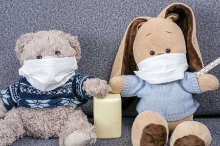 Stop Virus COVID -19. Toys bear and bunny are sitting in medical protective masks. Virus protection concept. Teddy bear and bunny hold soap in their paws,  concept of hand washing to protect against virus. Stop virus using soap and protective masks.の写真素材