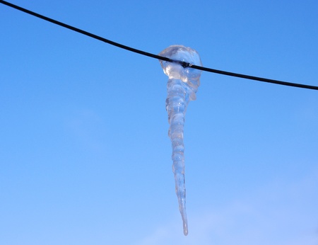 Brilliant icicle on electric wire in  winter against the blue skyの写真素材