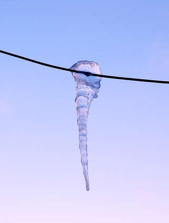 Brilliant icicle on electric wire in  winter against the blue skyの写真素材