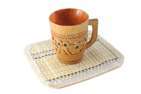 Carved wooden cup with a pattern on a bamboo mat isolated on white backgroundの写真素材
