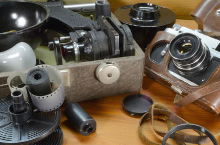Old film camera, a suitcase with a photo enlarger and other accessories on a wooden background.の写真素材