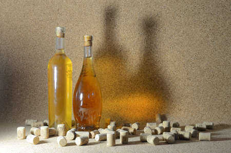 Two bottles of homemade wine on a cork background, surrounded by spilled wine corks.の写真素材