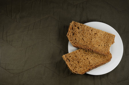Fresh rye bread on a white saucer, brown fabric background.の写真素材