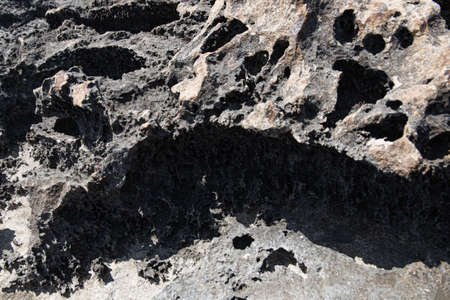 the rocky seashore in the form of rocks and depressions, against the background of the rock, as an...