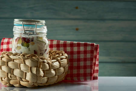 Jar of fresh yogurt with the fruits and berries inside it on a blue wooden background.の写真素材