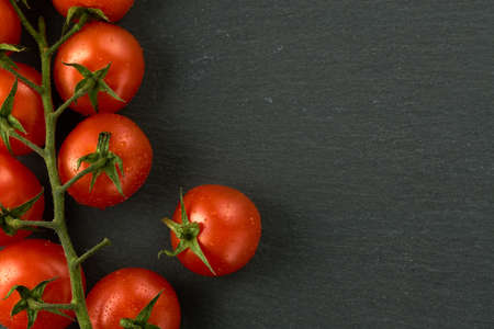 Cherry tomatoes on a black stone table flatlay. Image can be used as a texture as well, I left some space for the text on the right side.の写真素材
