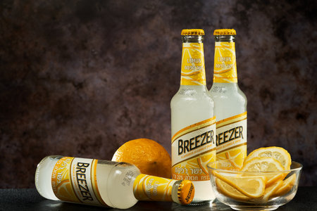 Tel-Aviv,Israel - 20.04.21. Bacardi breezer light alcohol beverage in lemon taste with the fresh lemon and lemon cuts inside the glass plate.のeditorial素材
