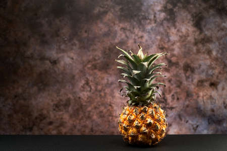 Yellow fresh pineapple on a table against the dark background.の写真素材