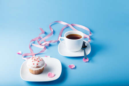 Colorful muffin on saucer with flower petal and ribbonの写真素材