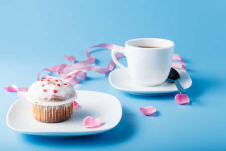 Colorful muffin on saucer with flower petal and ribbonの写真素材