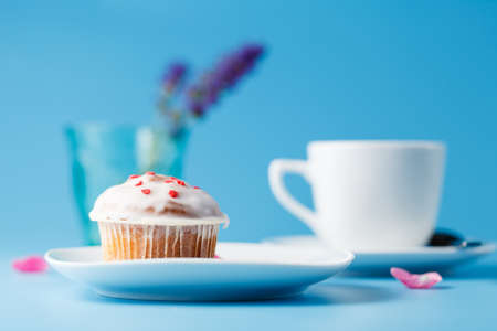 Colorful muffin on saucer with flower petalの写真素材