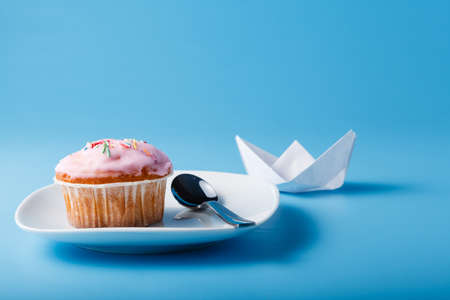 Colorful muffin on saucer with paper boat. Blue backgroundの写真素材
