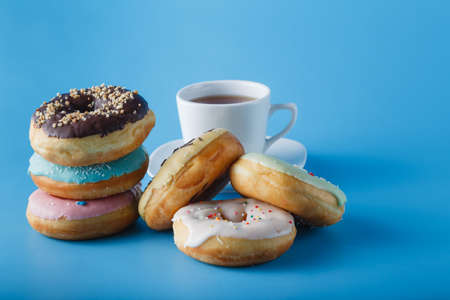 Six donuts on blue shadeless background with cup of teaの写真素材
