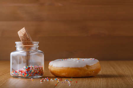 White sugar iced donut with bottle of nonpareilsの写真素材