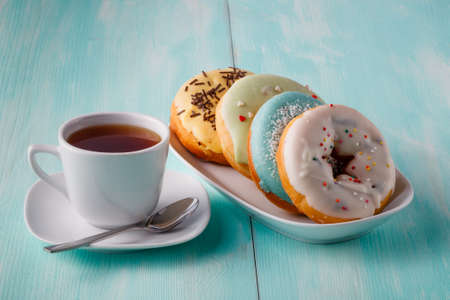 Four donuts on old wood table with cup of teaの写真素材