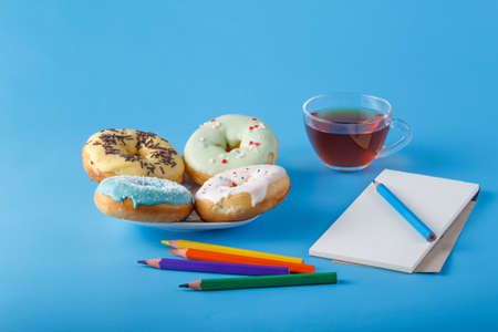 Donuts with tea cup and open sketchbookの写真素材
