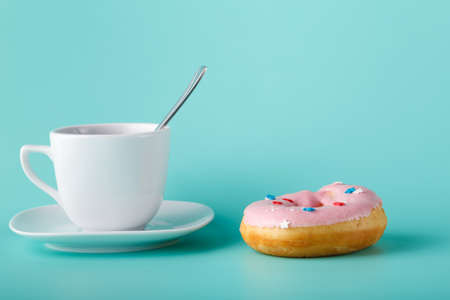 Four donuts on saucer with cup of tea. Aquamarine backgroundの写真素材