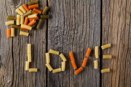 Word Â«loveÂ» laid out from pasta on a rustic boardsの写真素材