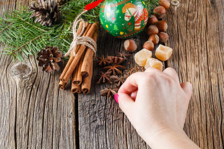 Female hand puts christmas spices, chinnamon, aniseの写真素材