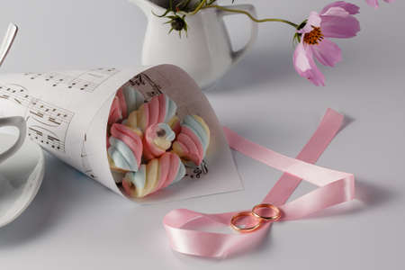 Wedding concept. Twisted marshmallow on white background and paped bag wth cup of coffeeの写真素材