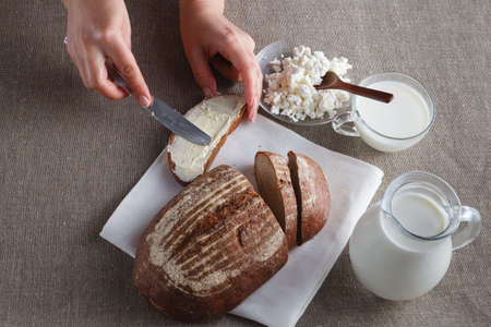 Female hand put butter on bread with milkの写真素材