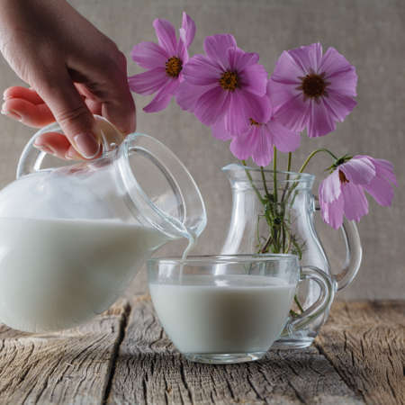 Cup of milk on wooden table with flowersの写真素材